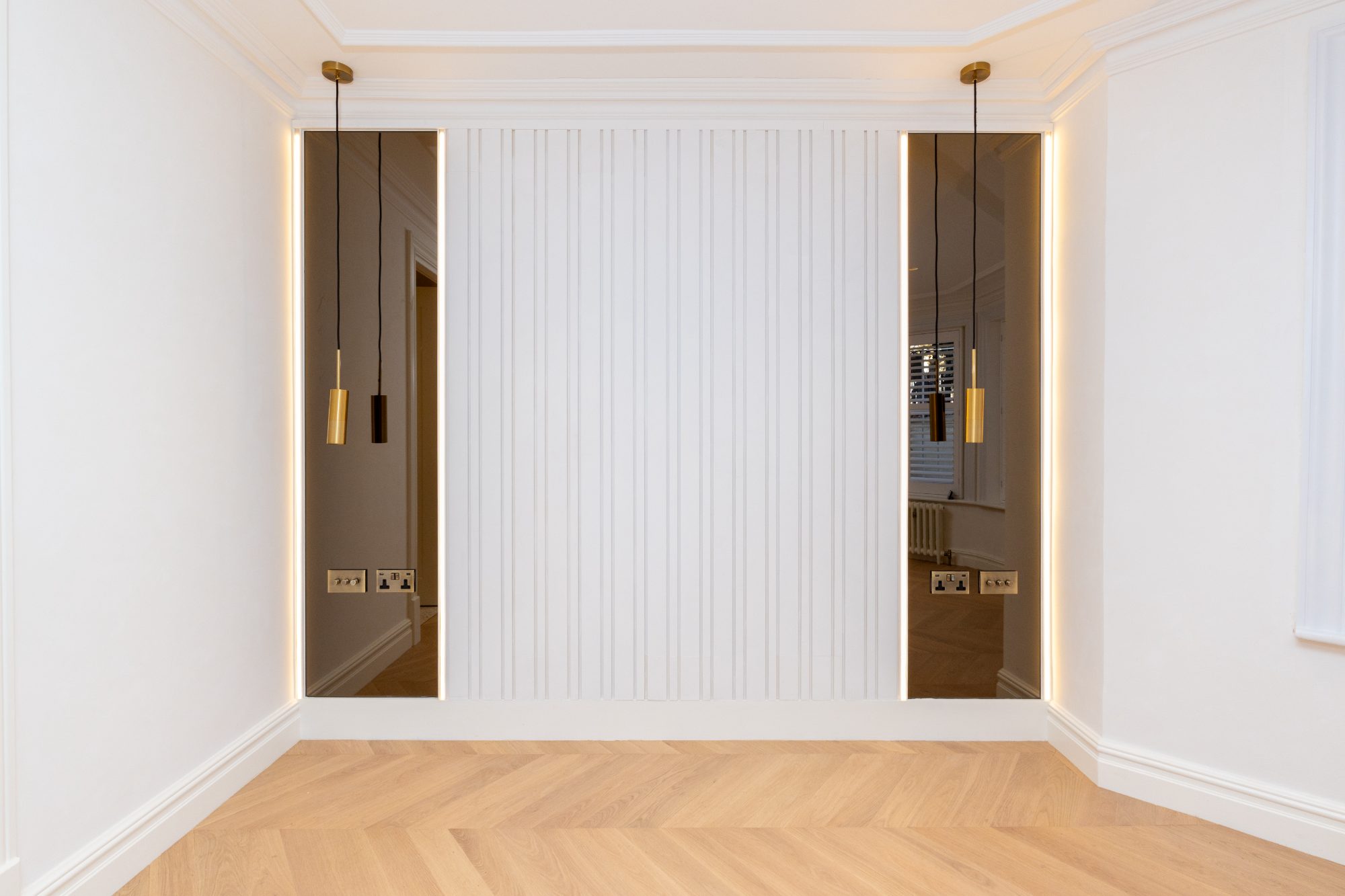 Fluted panelling flanked by two backlit full-height bronze mirrors