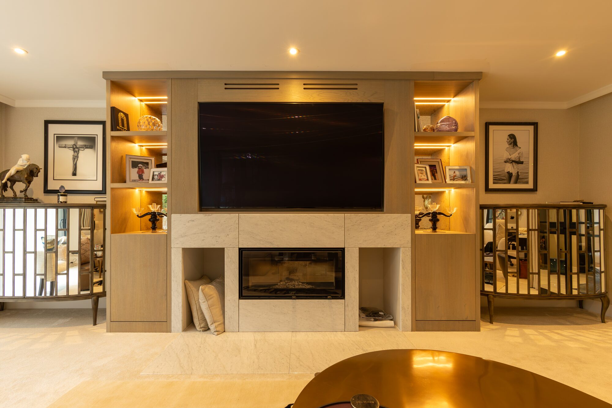 Oak media wall with lit display alcoves either side of a stone fire surround